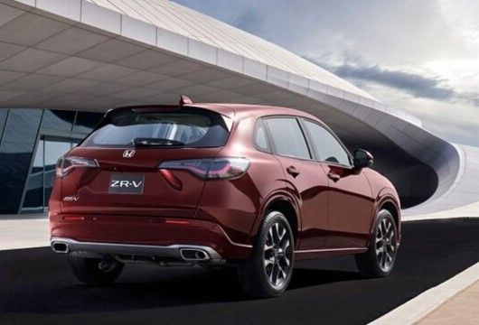 Rear view of a red Honda ZR-V, a compact crossover parked in front of a building with a curved roof.