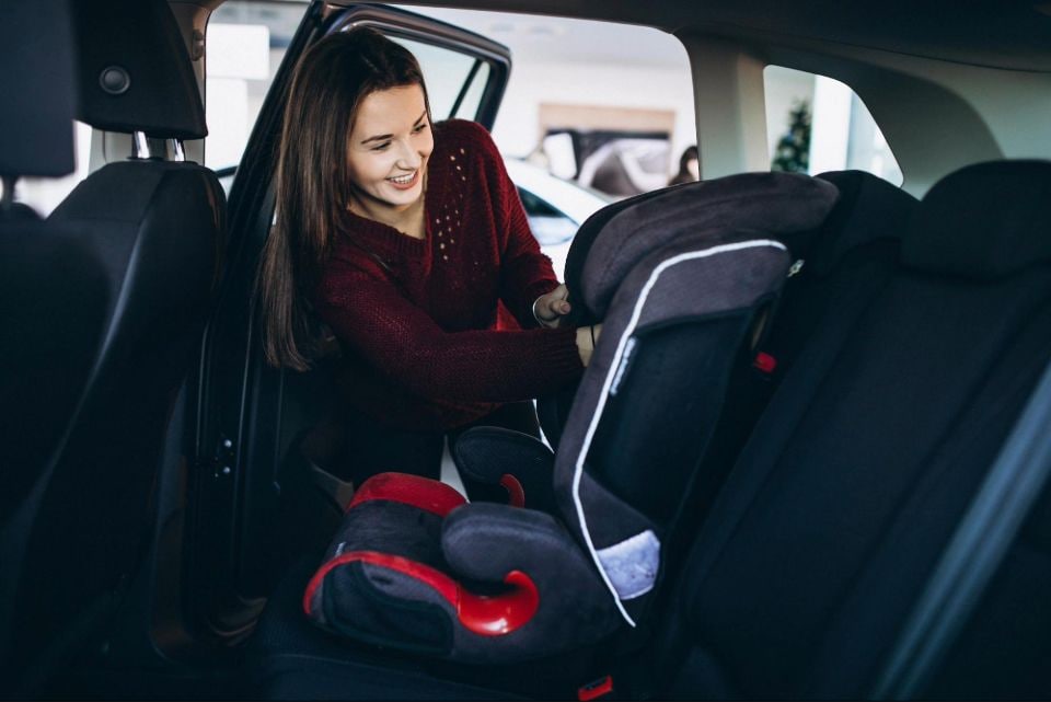 A women installing child safety car seat in the car