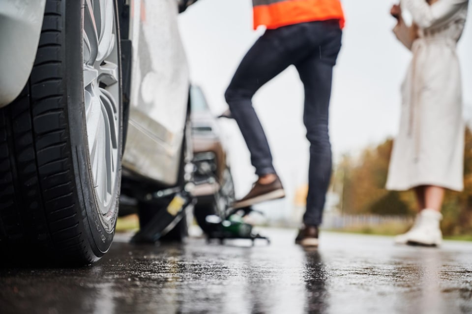 Emergency auto mechanic repairing woman's vehicle on the street