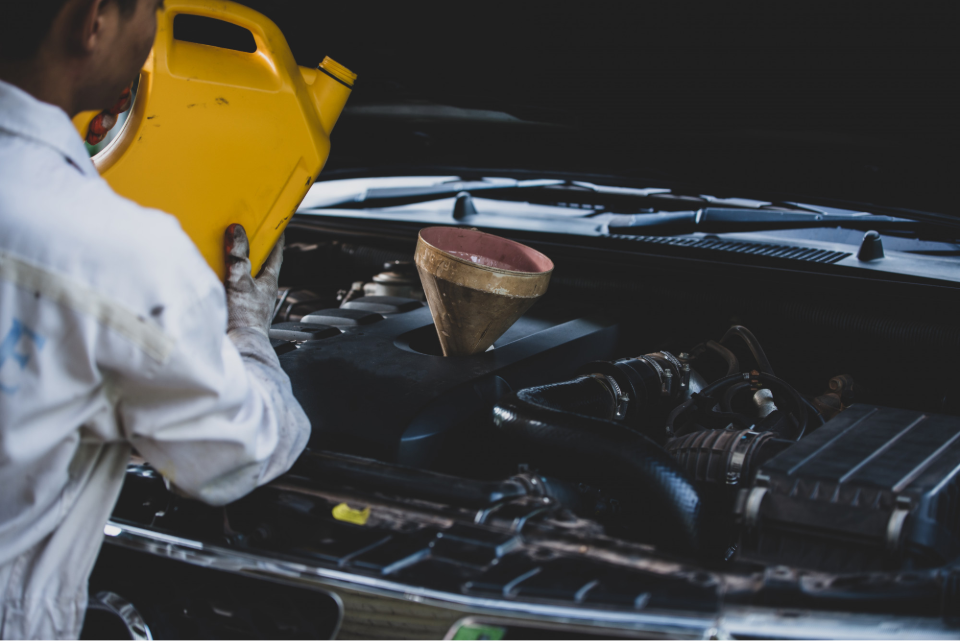 A mechanic hand pouring and replacing fresh oil into car engine at auto repair garage