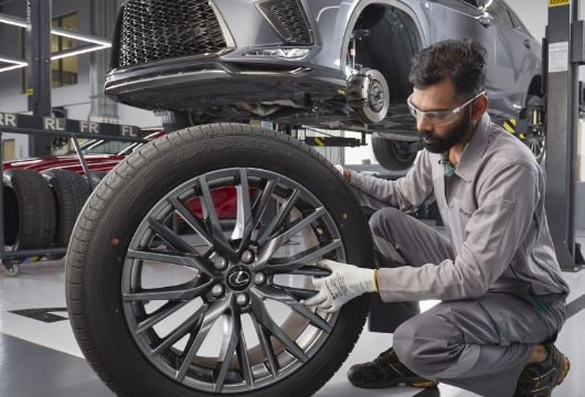 Lexus technician inspecting and fitting a car wheel at service center