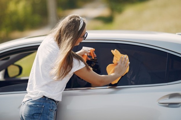 A woman wiping her tinted window 