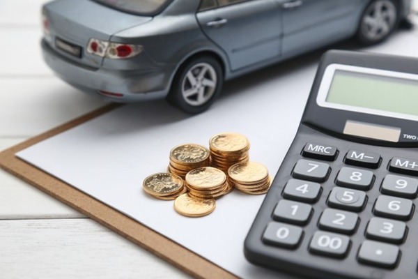 A calculator and coins by a model car on a desk