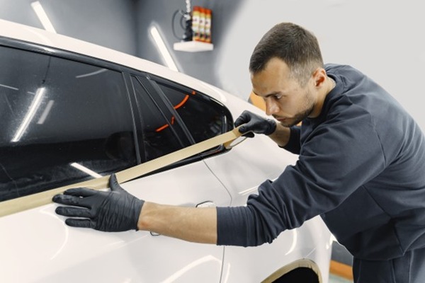 A man installing a tint on a car window