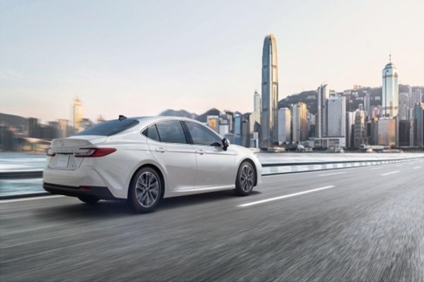 A white Toyota Camry hybrid on a city road