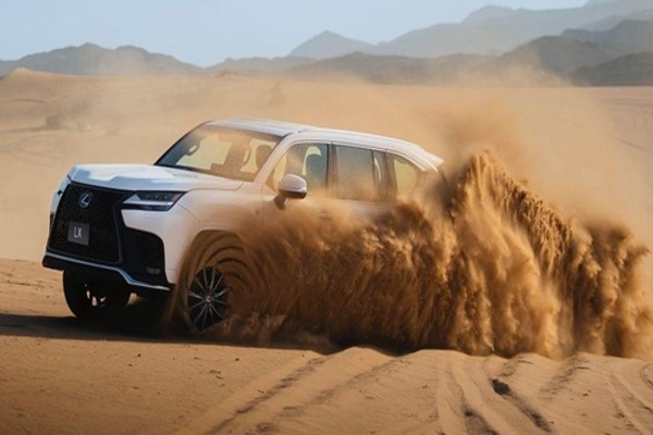 A Lexus LX SUV driving through a sandy dessert