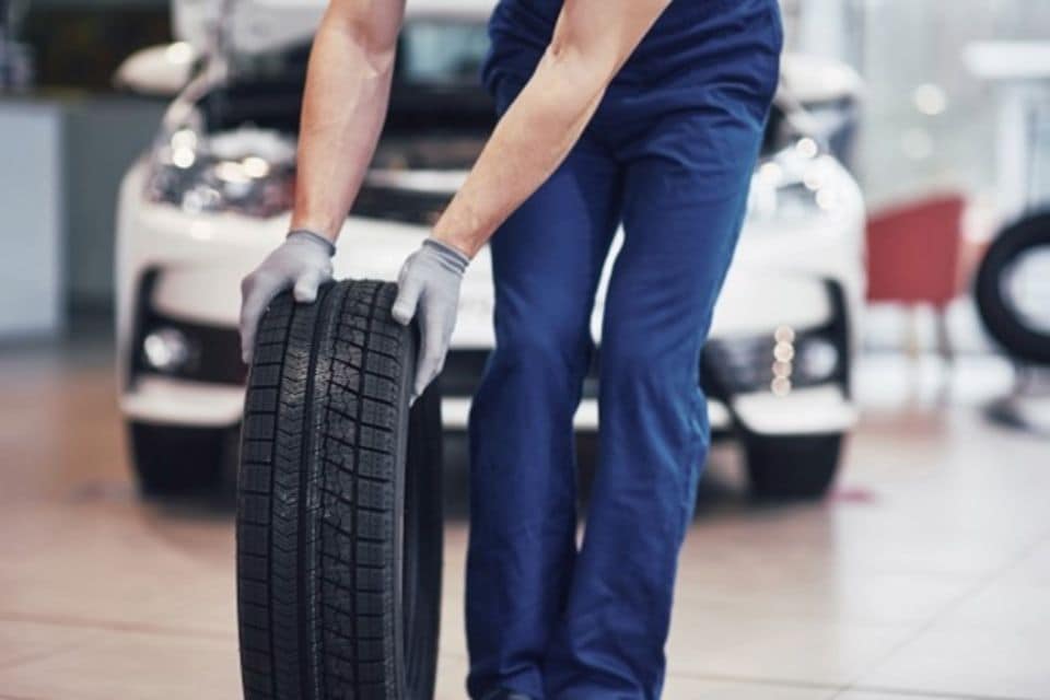 A man rolling a spare wheel across a service center