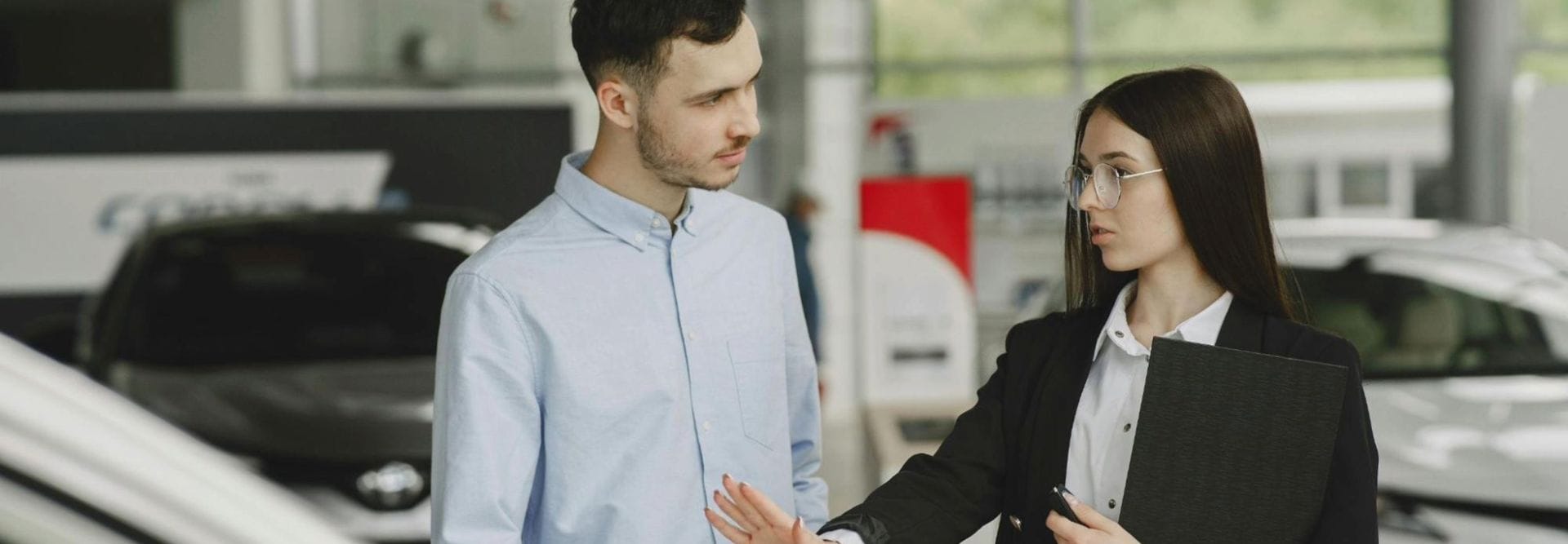  Sales agent talking to a customer in a car showroom