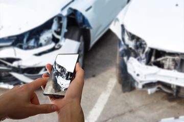 Person reporting traffic accident with pictures on mobile phone