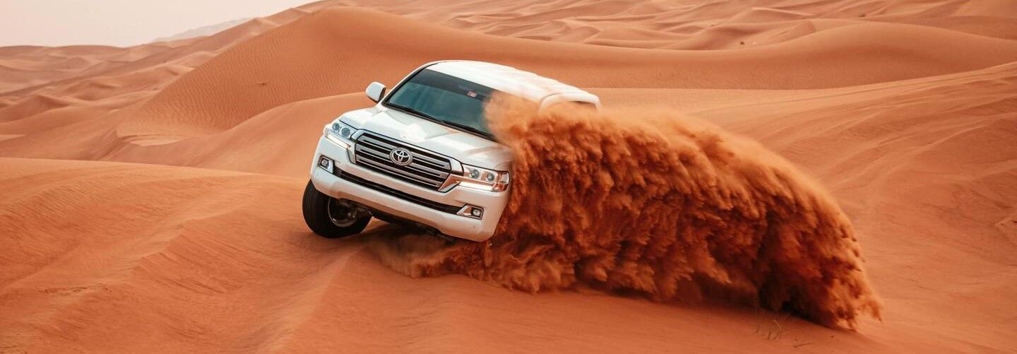 سيارة تويوتا بيضاء تسير على الكثبان الرملية