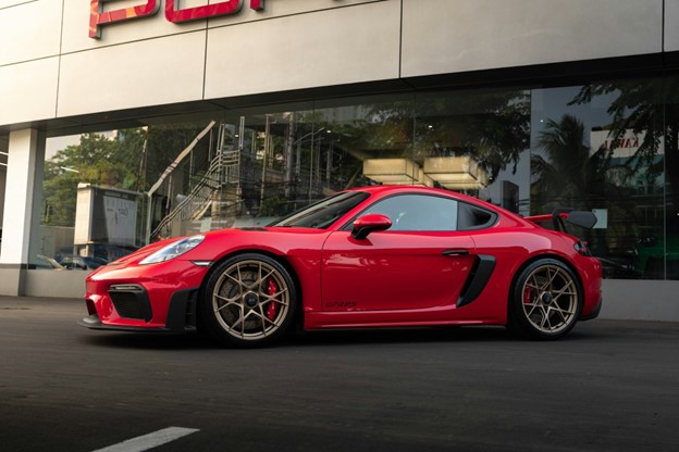 Side View of a Red Porsche 718 Parked in front of the showroom