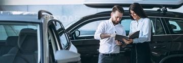 Salesman and woman looking for a car in a car showroom