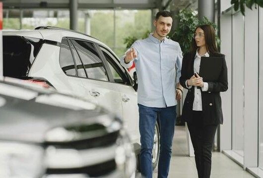 شخصان أنيقان داخل صالة عرض سيارات.