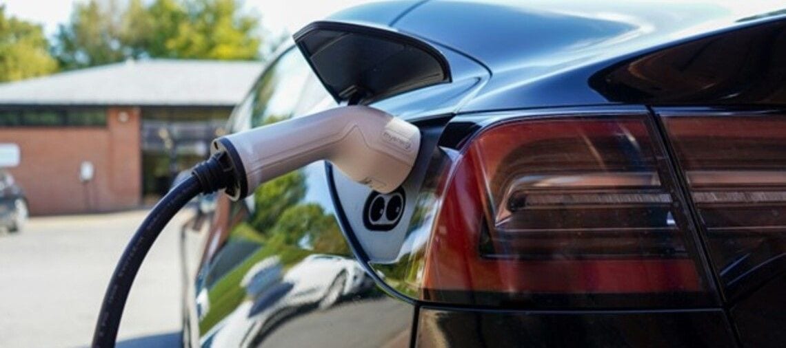 Black electric car being charged on the charging station