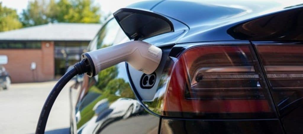 Black electric car being charged on the charging station