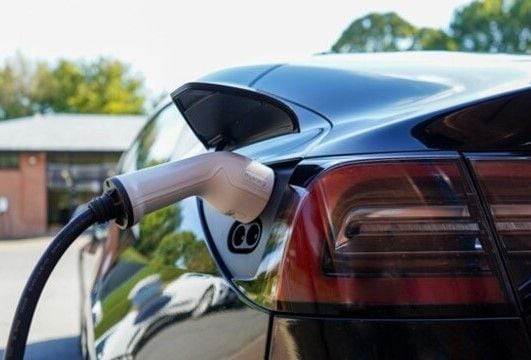 Black electric car being charged on the charging station