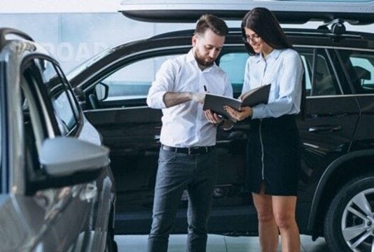 Salesman and woman looking for a car in a car showroom