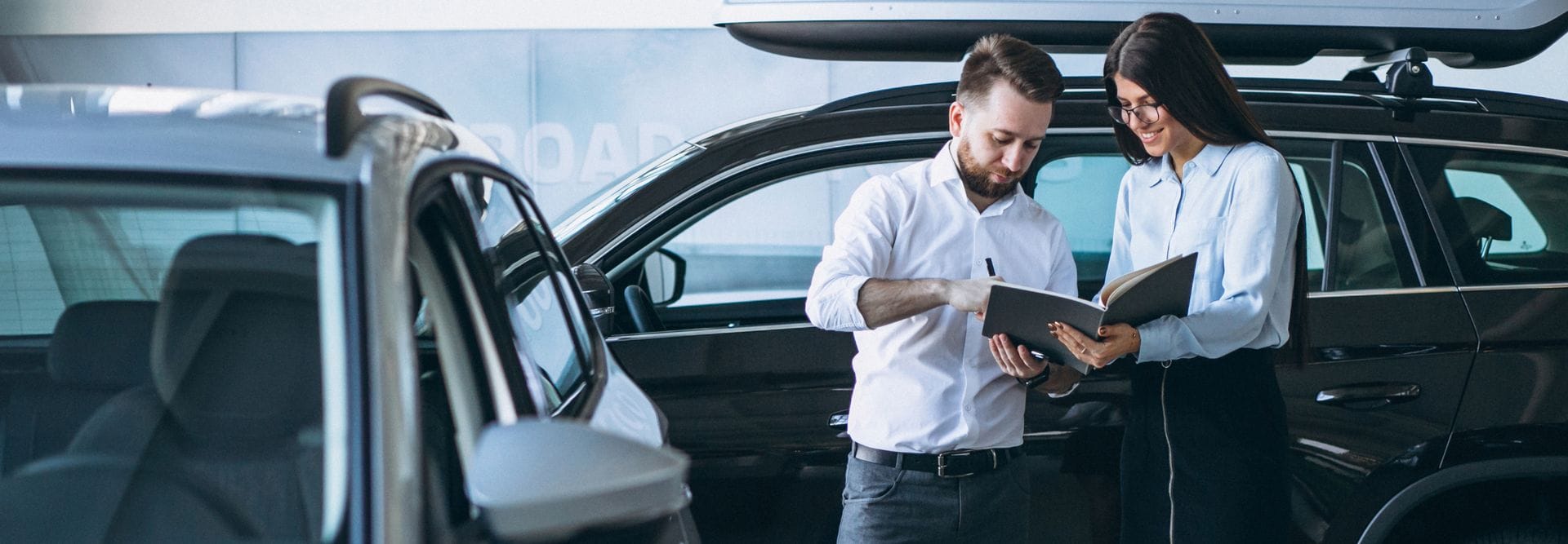 Salesman and woman looking for a car in a car showroom