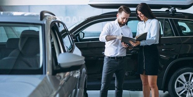 بائع وامرأة يبحثان عن سيارة في معرض سيارات